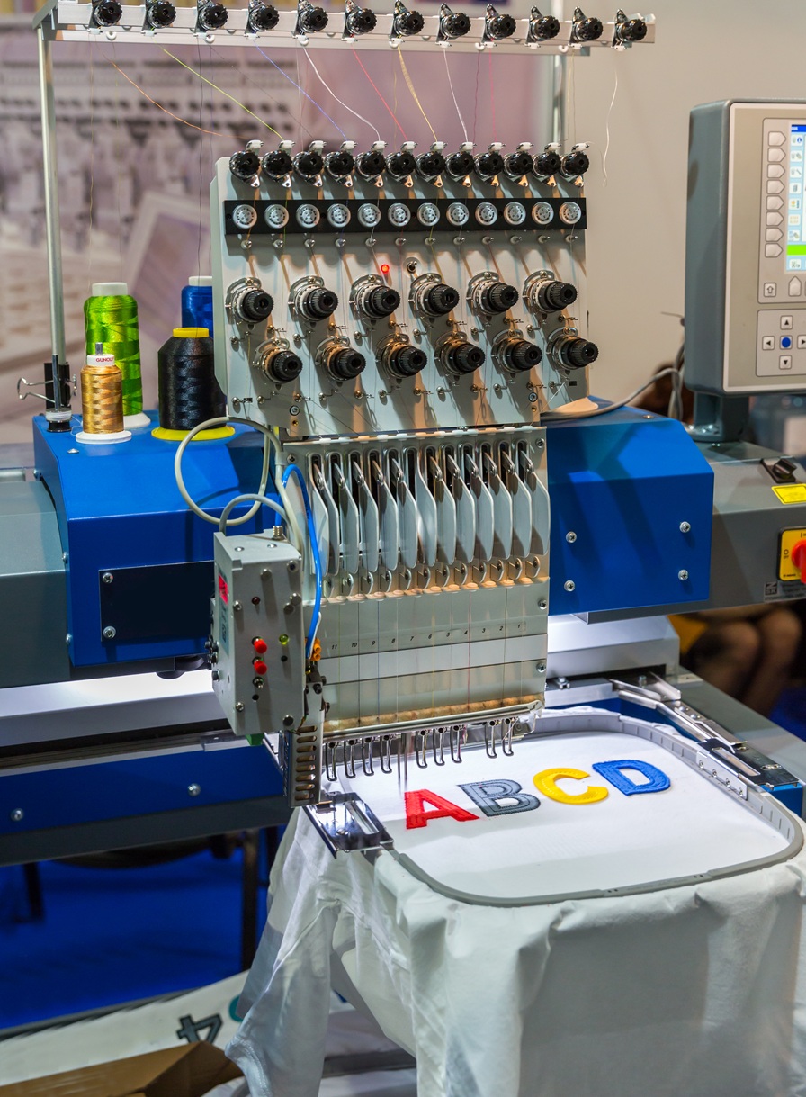 Professional sewing machine embroidery color letters. Textile fabric, nobody. Factory production, sew manufacturing, needlework technology